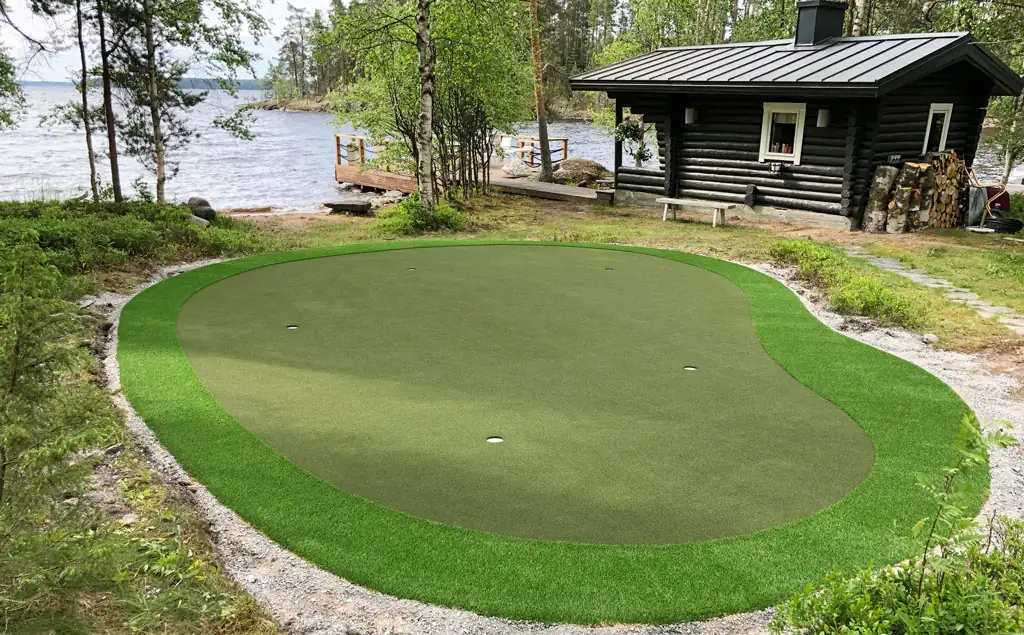 Mökkiviheriö hirsisaunan edessä järven rannalla, ympärillä metsää.