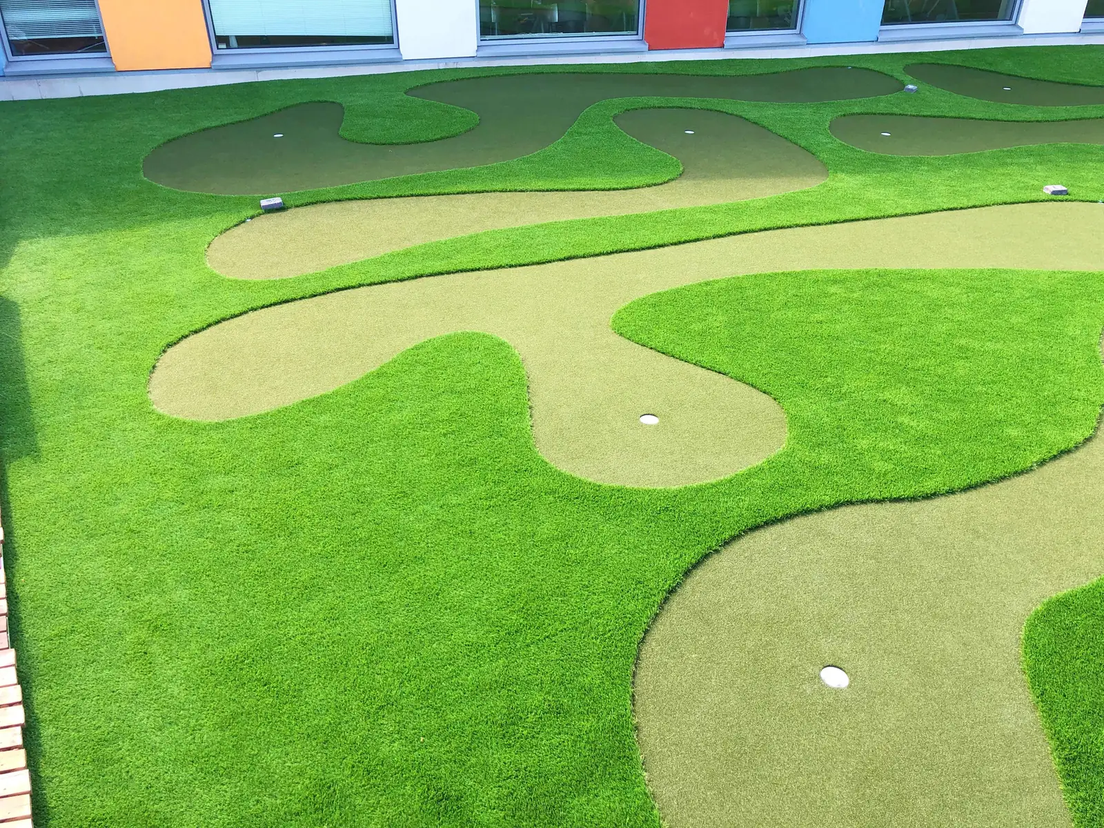 Kiemurtelevat minigolfväylät ravintolan kattoterassilla ylhäältä kuvattuna.
