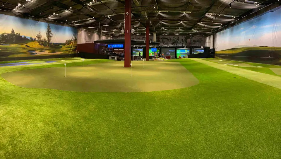 GoGolf Loungen halli: iso puttiviheriö, golfkenttämaalaukset seinillä ja simulaattorit takaseinällä.