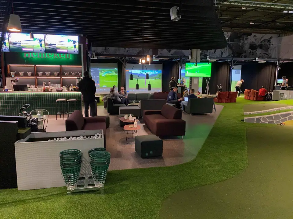GoGolf Loungen halli: oleskelutila, viheriöitä ja simulaattoripaikat taustalla.