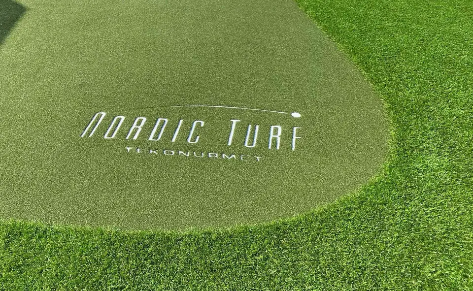 Vaaleampi viheriö ja Nordic Turfin logo tekonurmipihalla.