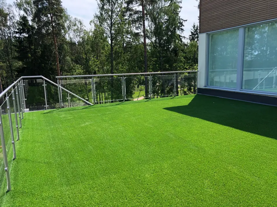Tekonurmipiha lasikaiteen ja modernin talon vieressä.
