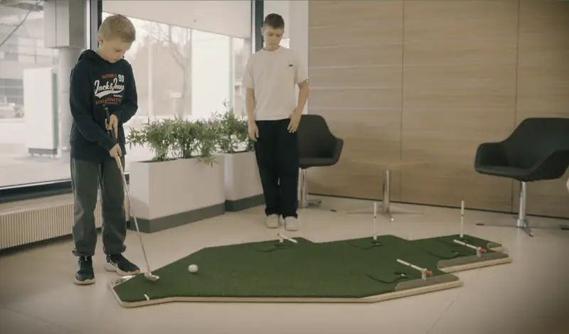 Kaksi poikaa pelaa DeadEye Challenge -puttipeliä aulassa.